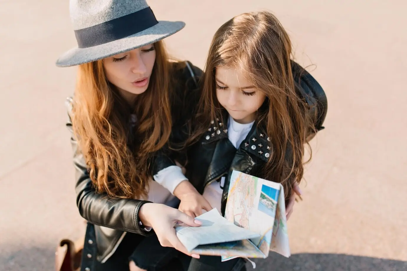 An elegant young woman and her daughter are lost in an unfamiliar city and consult the map. The cute little girl, with a serious expression, comes up with the trip route together with her beautiful mother.