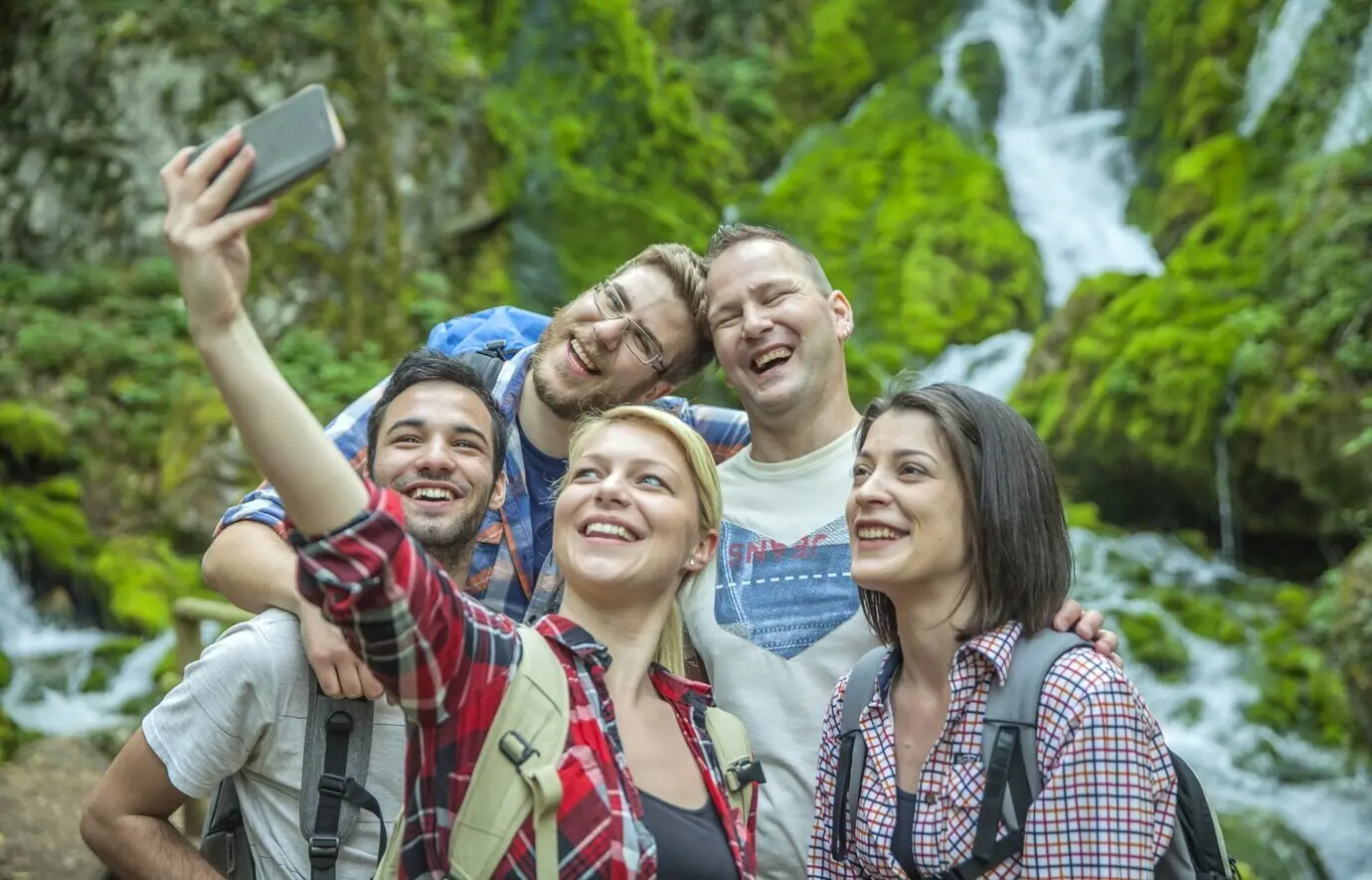 A group of friends having a good time and taking selfies out in nature.